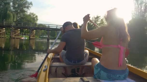 FLARE DE LA LENTE: Los rayos de sol dorados del verano brillan sobre dos turistas remando en una canoa. — Vídeos de Stock