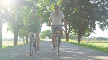 Çift, güneşli caddede bisiklet sürerek aktif bir randevunun tadını çıkarıyor.