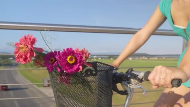 Sluiten omhoog: Gelukkig vrouw rijdt haar fiets met een mooi boeket in de mand. — Stockvideo