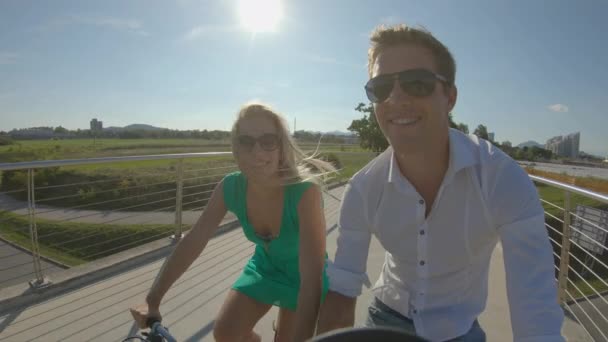POV : Un bel homme et sa copine font du vélo sur un pont moderne. — Video