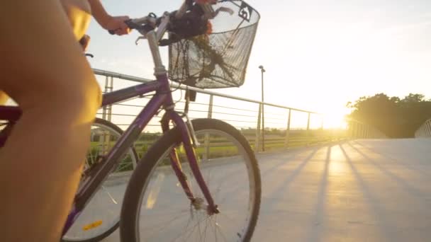 低角度:認識できないカップルが日没時に陸橋を渡って自転車に乗る — ストック動画