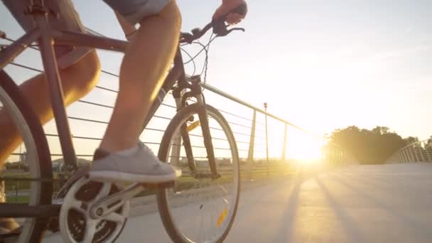 LENS FLARE: Unbekannter tritt bei Sonnenaufgang mit seinem Fahrrad über eine Überführung. — Stockvideo