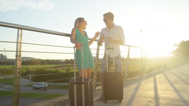 レンズフレア:若い新婚旅行は興奮して晴れた日に空港シャトルを待っています — ストック動画