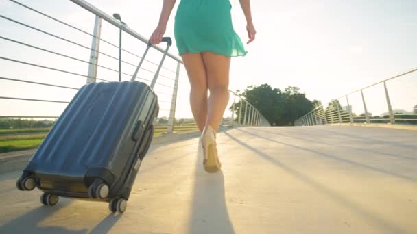 Egy fiatal nő cipeli a bőröndjét a reptérre magassarkúban. — Stock videók