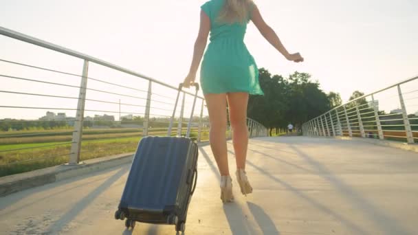 LENS FLARE: Vrouwelijke reiziger op hoge hakken loopt over brug en naar de luchthaven — Stockvideo