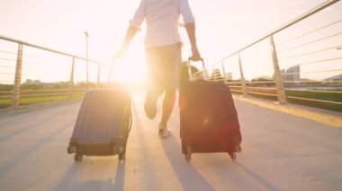 Havaalanına geç gelen erkek turist, bavullarıyla üst geçitten geçiyor.