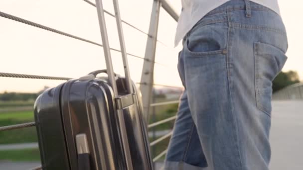Турист тримається за свою валізу, чекаючи таксі на заході сонця.. — стокове відео