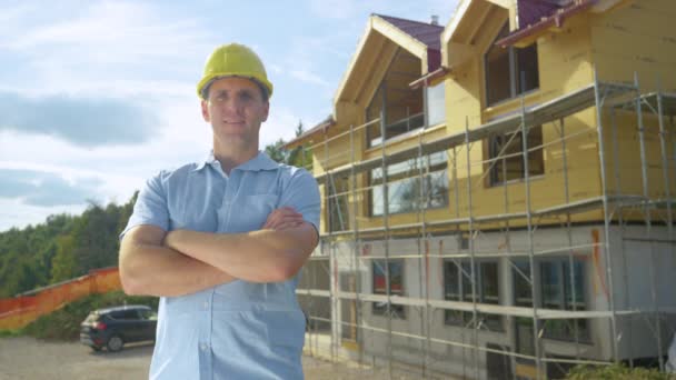 Bezárás: Mosolygós vállalkozó büszkén áll a ház előtt építés alatt — Stock videók