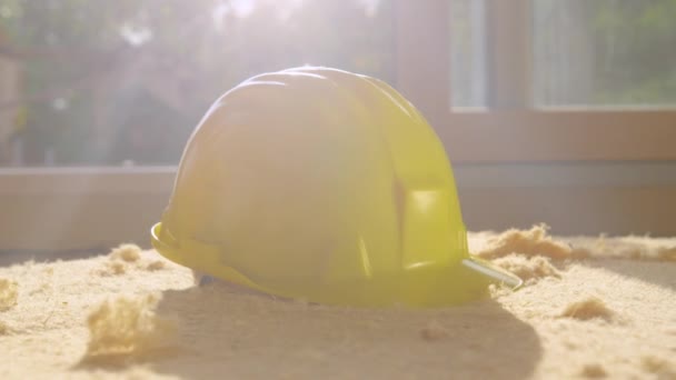 CLOSE UP Bright spring sun shines on a yellow hard hat sitting on sheet of foam — Stock Video