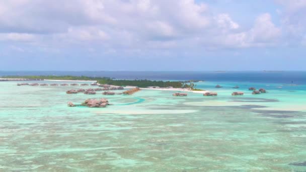 AERIAL: Πετώντας προς ένα νησί στις Μαλδίβες με εγκαταλελειμμένες βίλες πάνω από το νερό. — Αρχείο Βίντεο