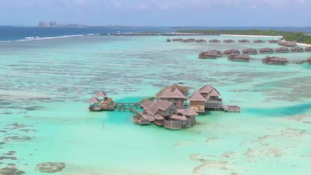 AERIAL: Fotografía cinematográfica de bungalows de madera de lujo cerca de una remota isla exótica. — Vídeos de Stock
