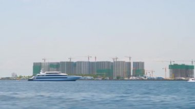 Lüks yat, gökdelen şantiyeleriyle dolu erkek sahil şeridini geçiyor..