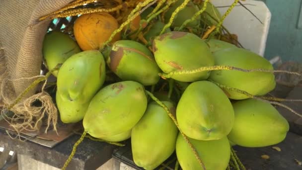 CERRAR, DOF: Una rama llena de cocos verdes maduros se encuentran en la mesa de madera . — Vídeos de Stock