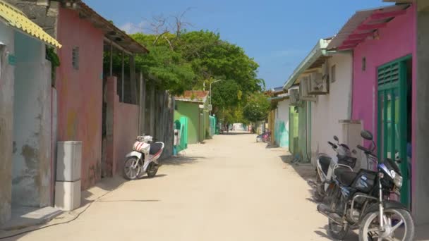 Vista panorâmica de uma estrada de terra vazia que passa por casas locais coloridas em Maldivas — Vídeo de Stock