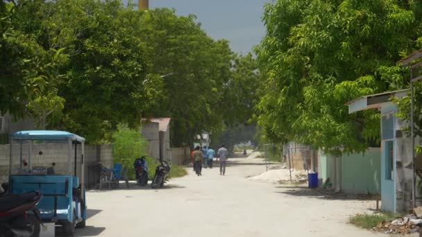 スローモーション:地元の人々はモルディブの未舗装の道路を歩いています. — ストック動画