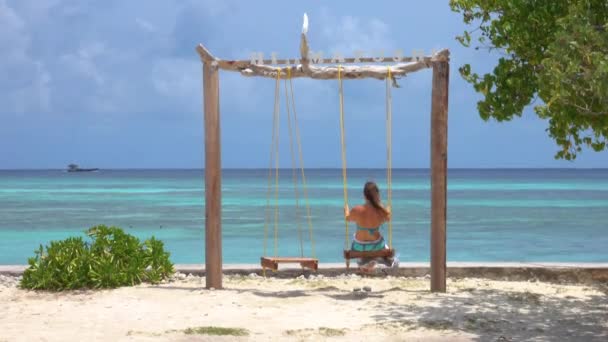 AFSLUITEN: Onherkenbare vrouwelijke toeristische schommels en observeert het tropische strand — Stockvideo