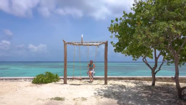 Radostná dívka houpe na romantické houpačce na bílé písečné pláži na Maledivách. — Stock video