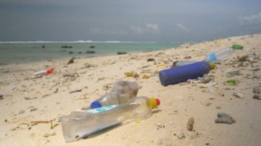 Boş plastik şişeler tropikal beyaz kumsala taşar..