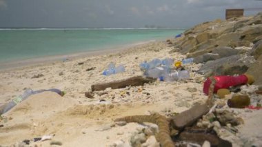 Turkuaz okyanus beyaz kumsal şeridine plastik atıkları saçıyor.