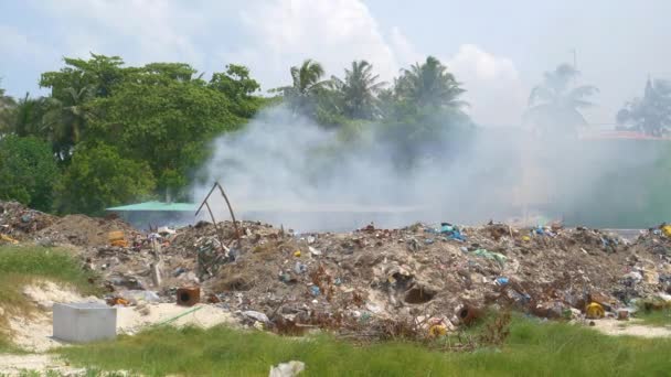 Una discarica piena di spazzatura sta bruciando rifiuti nel mezzo di una foresta tropicale. — Video Stock
