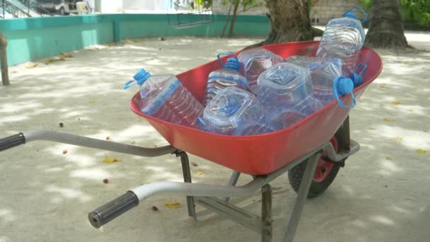 CLOSE UP: Колісниця наповнена пляшками, коли люди чекають доставки води . — стокове відео