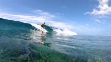 Havalı sörfçü adam kristal berrak okyanus dalgalarıyla tropik bir adaya gidiyor.