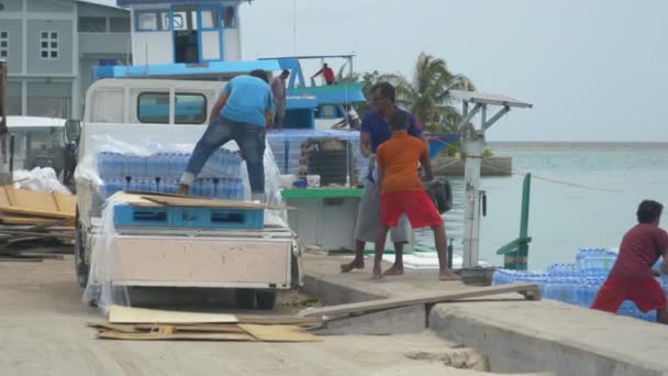 MOCIÓN LENTA: Los locales cooperan para descargar el camión y cargar un barco con agua embotellada — Vídeo de stock