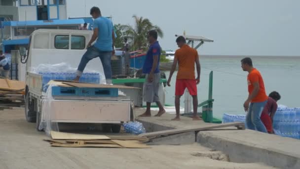 Ock werknemers laden een boot met plastic pakketten van gebotteld water. — Stockvideo