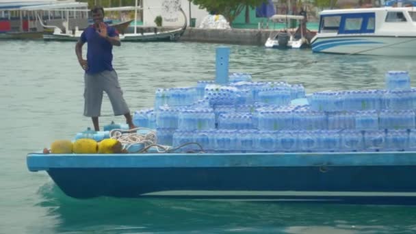 PORTRAIT: Человек, стоящий перед лодкой волны во время транспортировки бутилированной воды — стоковое видео