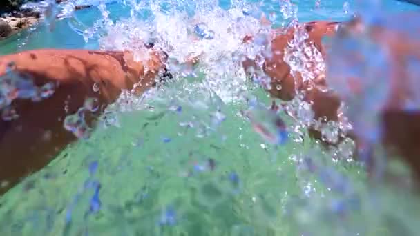 Человек ныряет в бирюзовую океанскую воду, окружающую тропический остров — стоковое видео