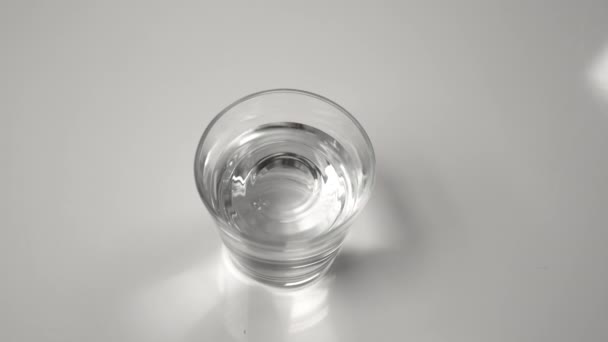 CLOSE UP: Een klein glas gevuld met water shakes tijdens een aardbeving. — Stockvideo