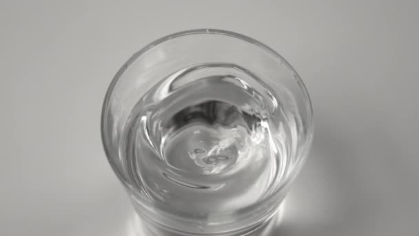 CHIUSURA: schizzi di acqua tonda all'interno di un vetro trasparente durante un evento sismico. — Video Stock