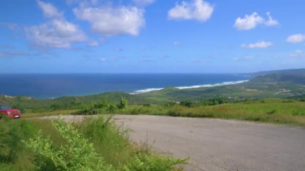 Tourist in red jeep drives up a scenic road overlooking the tropical coast. — Stock Video