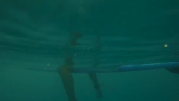 Half Underwater: Surfer κορίτσι κάθεται σε longboard, ενώ περιμένει για τα κύματα στο ηλιοβασίλεμα — Αρχείο Βίντεο