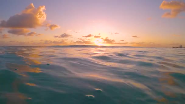 FERMER : Les rayons de soleil dorés du soir brillent sur la vague océanique qui balaie la caméra. — Video
