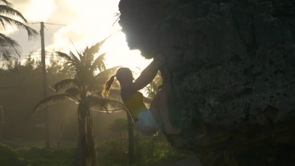 LENS FLARE Nieustraszona kobieta wspina się na klif oświetlony złotym popołudniowym słońcem — Wideo stockowe
