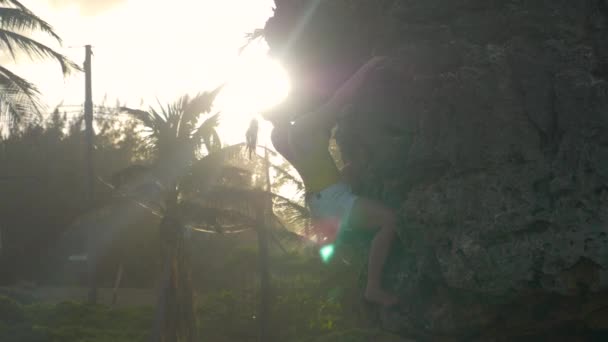 CERRAR: Brillantes rayos de sol de verano brillan en la escalada en roca turística femenina activa. — Vídeo de stock