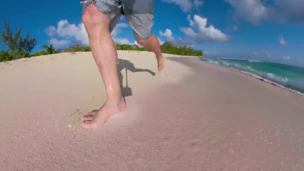 BAIXA ÂNGULO: turista masculino irreconhecível corre descalço ao longo da praia tropical. — Vídeo de Stock