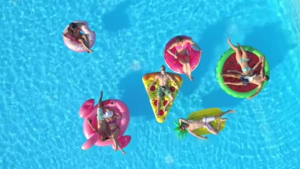 DRONE: Turisté relaxují na barevných plovácích a zároveň si užívají slunečného dne v bazénu. — Stock video