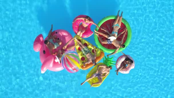 Друзья, отдыхающие на поплавках, собираются вместе во время отдыха в бассейне — стоковое видео