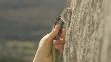 Kaya tırmanışçısı bir karabinayı vidalanmış bir cıvataya takar..