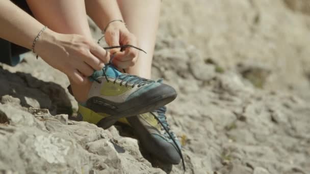 CLOSE UP: Unerkannte Frau schnürt Kletterschuhe, bevor sie einen Felsbrocken besteigt — Stockvideo