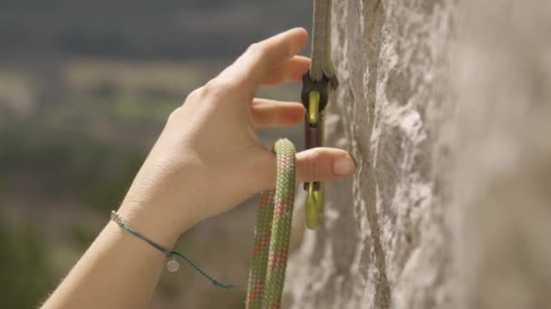 CLOSE UP, DOF: Fit woman top roping loops her rope into a safety carabiner. — Stock Video