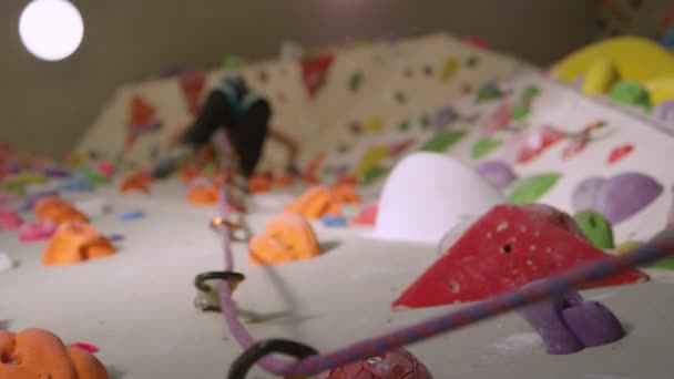 FERMER : Corde bouclée à travers les mousquetons balance comme fille grimpe vers le haut mur intérieur