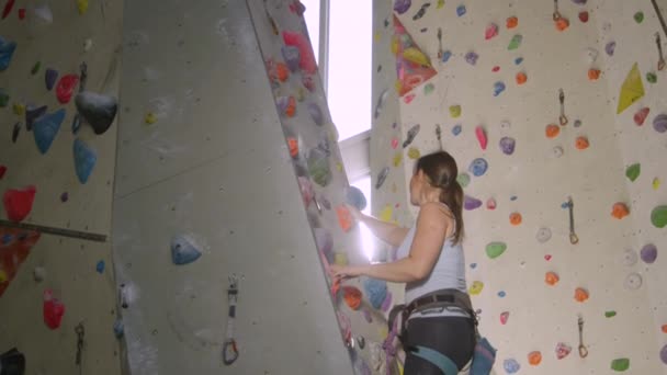 LENS FLARE: Klara solstrålar skina på en flicka klättra en rutt i en inomhus centrum — Stockvideo