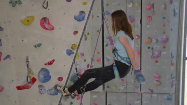 CLOSE UP: Young girl climbing indoors chalks up before continuing her ascent. — Stock Video