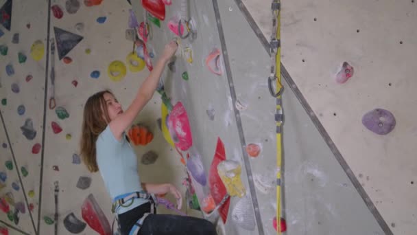 CLOSE UP: Ervaren blanke tiener klimmen een moeilijke indoor route — Stockvideo