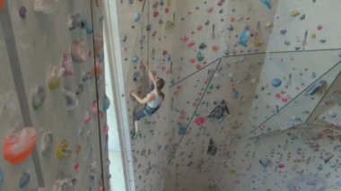 DRONE: zinde genç bir kadın, kapalı bir tırmanma merkezinde zorlu bir rota ölçer.