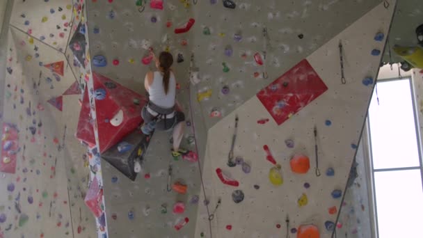 SLOW MOTION: kvinnliga klättrare glider samtidigt som man försöker greppa en rosa sluttning grepp. — Stockvideo