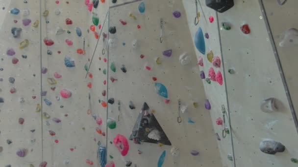 AERIAL: Wände einer Kletterhalle gefüllt mit bunten magnesiumbeschichteten Griffen. — Stockvideo